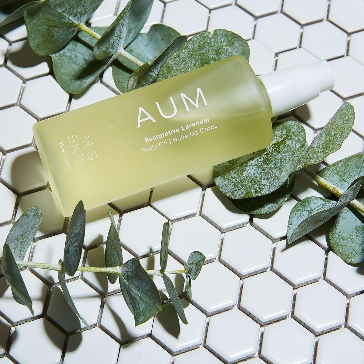 M.S Skincare AUM Lavender Restorative Body Oil -luxury skincare in a frosted white bottle on tile with eucalyptus leaves